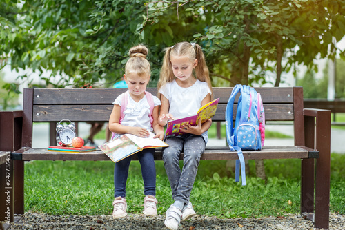 Two children read books in the school park. The concept of school, study, education, friendship, childhood