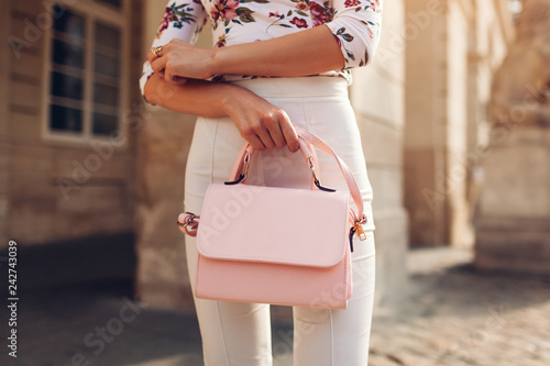 Close-up of stylish female handbag. Young woman wearing beautiful outfit and accessories outdoors. City fashion
