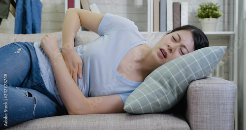 Young woman on couch with hard stomachache