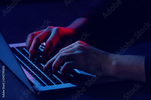 Professional hacker with laptop sitting at table, closeup