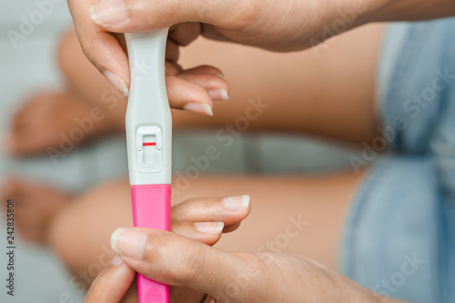 Unhappy young asian woman holding pregnancy test showing a negative result in her bathroom, wellness and healthy concept, infertility problem,Selective focus.