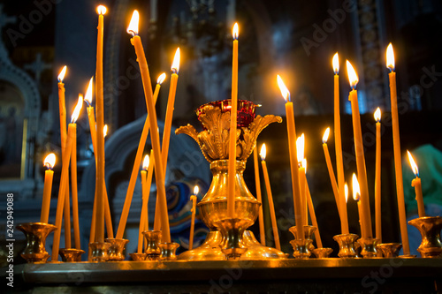 Many burning wax candles in the orthodox church or temple