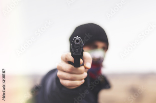 Criminal threatens with a gun closeup, crime concept
