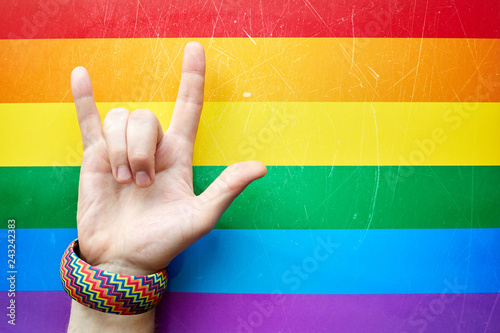 "I love you" in American sign language (ASL) which shows a man's hand on the background of the flag of LGBTQ (LGBT) community
