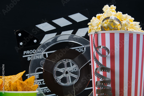 on a black background, a bucket of popcorn, a bucket of nachos, film and double for filming