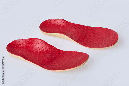 Orthotics on a white background. Insert in shoes to support the foot. Red leather medical insole 