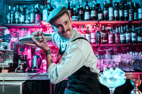 Expert barman is making cocktail at night club or bar. Glass of fiery cocktail on the bar counter against the background of bartenders hands with fire. Barman day concept