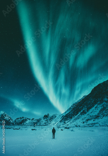 Young man watching Aurora Borealis in winter, Lofoten, Norway