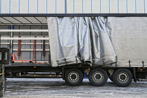 A semi-trailer with an exposed tarpaulin during unloading. Transport and unloading.
