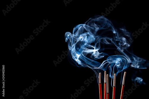 Smoking incense sticks on black background