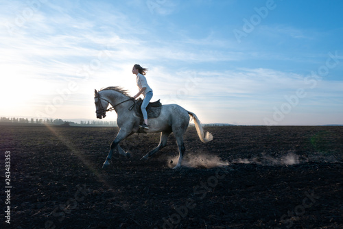 Girl and horse at sunset, jumping over the field