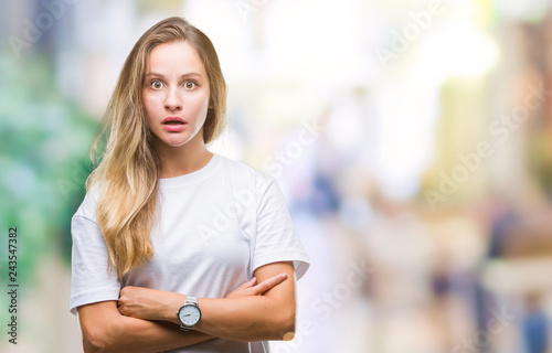 Young beautiful blonde woman wearing casual white t-shirt over isolated background afraid and shocked with surprise expression, fear and excited face.