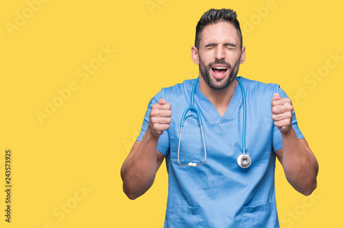 Handsome young doctor surgeon man over isolated background excited for success with arms raised celebrating victory smiling. Winner concept.