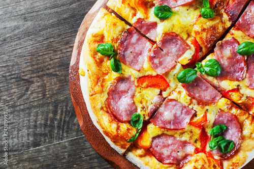 Pizza with Mozzarella cheese, ham, pepper, meat, Tomato sauce, Spices and Fresh Basil. Italian pizza on wooden background