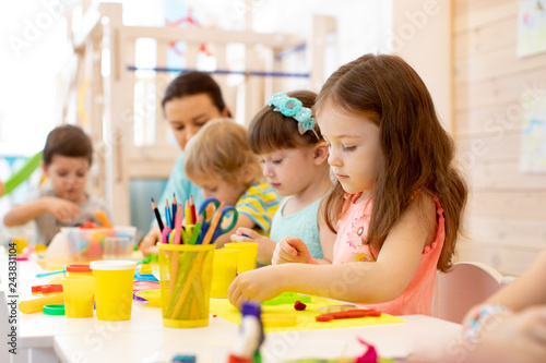 kindergarten children doing arts and crafts with teacher in day care centre