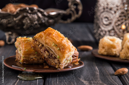 Close up, macro. Traditional honey baklava, nuts. Pottery and silverware. Dark wooden background.