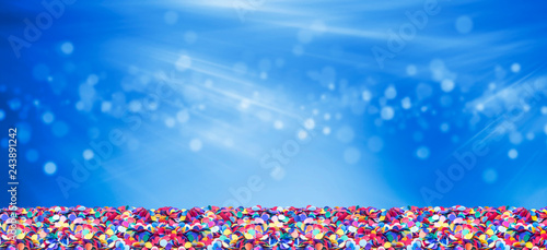 Colorful confetti in front of blue background with bokeh for carnival