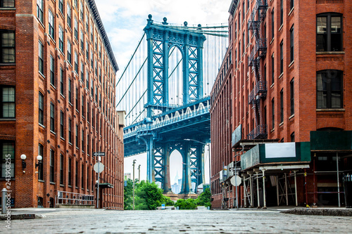 Manhattan Bridge between Manhattan and Brooklyn over East River seen from a narrow alley enclosed by two brick buildings on a sunny day in Washington street in Dumbo, Brooklyn, NYC