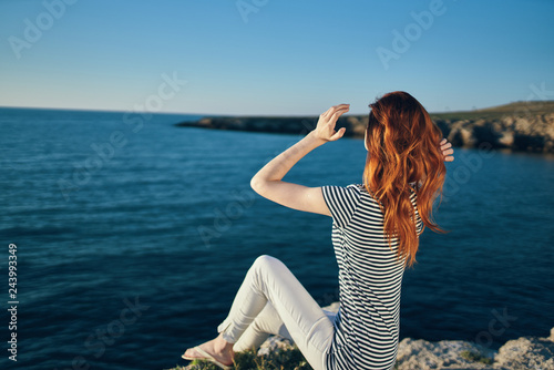 woman sits on the bank straightens her hair looks at the sea