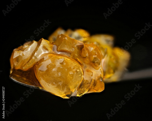 Cannabis concentrate diamonds and juice on dabbing tool on black background