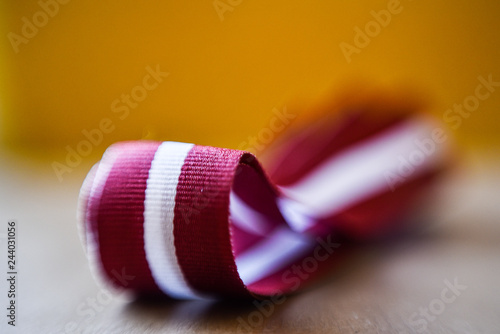 Latvia's flag ribbon on white blur background. Selective focus