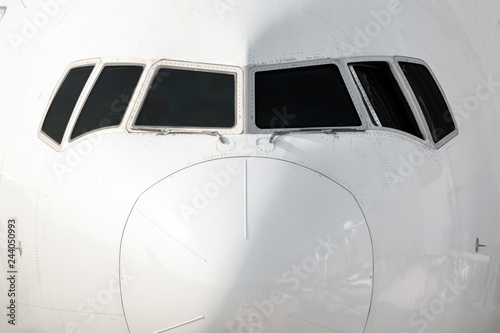 Close front outside view of a white big jet plane cockpit.