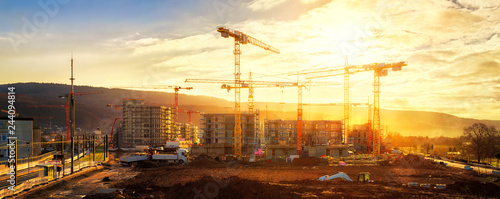 Large construction site including several cranes, with lots of gold sunlight