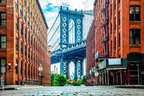 Manhattan Bridge between Manhattan and Brooklyn over East River seen from a narrow alley enclosed by two brick buildings on a sunny day in Washington street in Dumbo, Brooklyn, NYC