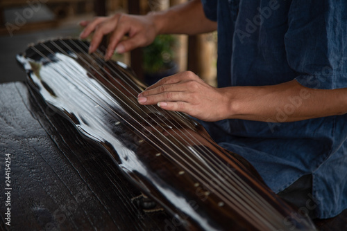 The man is playing the Guqin 