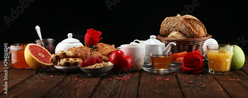 breakfast on table with bread buns, croissants, coffe and juice on valentines day.