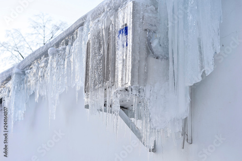 The back of the supermarket building has air conditioning on the wall covered with a thick layer of icicles.