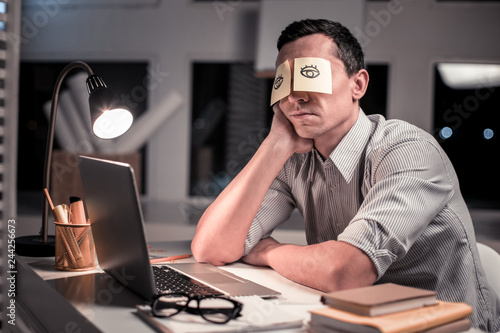 Pleasant tired man sitting at the table in the office