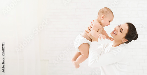 Young mom holding her happy baby in air