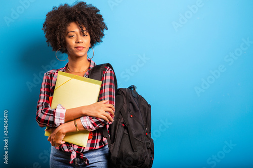 young african student with backpack on the back on blue background