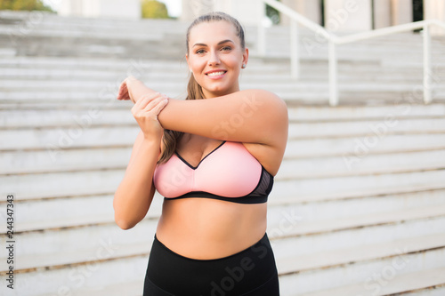 Portrait of smiling young woman stretching outdoors