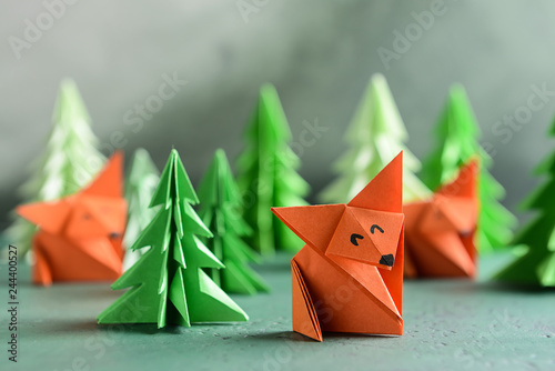 Origami foxes with fir trees on color table