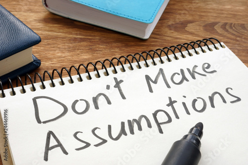 Don't Make Assumptions. Notepad with marker on a table.