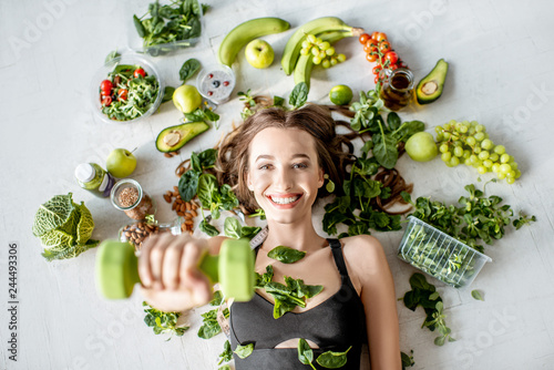 Beauty portrait of a sports woman surrounded by various healthy food lying on the floor. Healthy eating and sports lifestyle concept