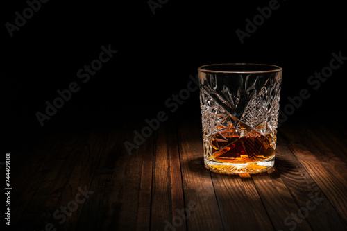 Crystal glass of whiskey on a wooden table on a black background. Snack for whiskey. Cheese, almonds, pear, apple, olives, orange peel.