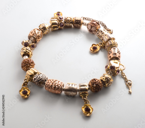 Gold color bracelet on a white background with a shadow