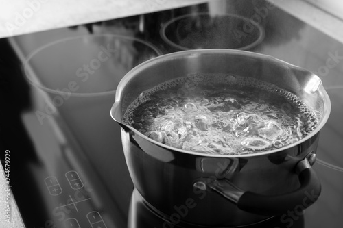 Pot with boiling water on electric stove, space for text