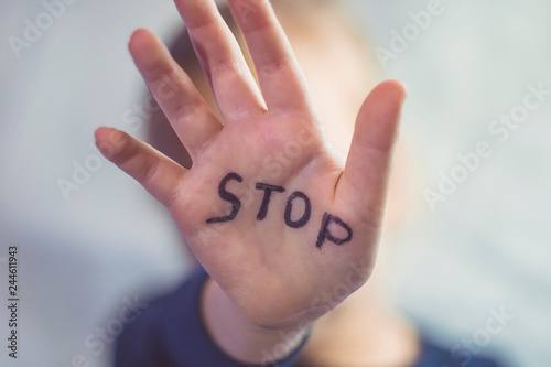 Concept of domestic violence and child abusement. A little girl shows her hand with the word STOP written on it. Children violence.