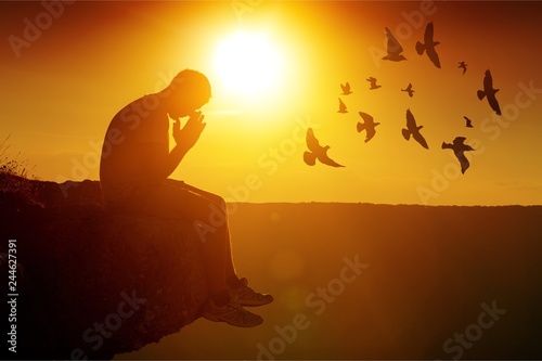 Young man pray outdoor on top of mountains in sunset