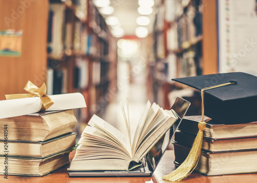 E-learning class and internet online education success with IT computer laptop, graduation hat, academic cap, mortarboard and degree certificate on books in class or library study room