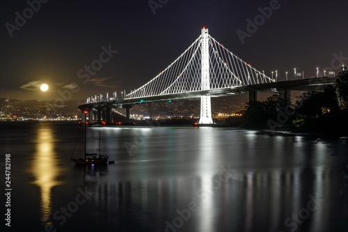 Full moon rising over the new eastern span of the San Francisco-Oakland Bay Bridge at night. Yerba Buena Island, California, USA.