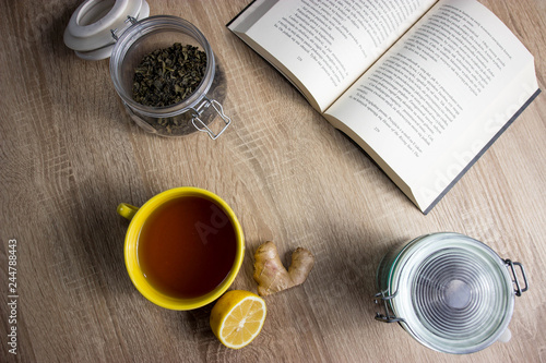 Tea with lemon and book. In left corner black and green tea in jars