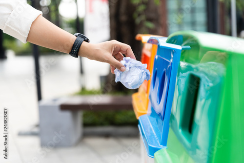 Closeup portrait woman hand throwing crumpled paper in recycling bin.