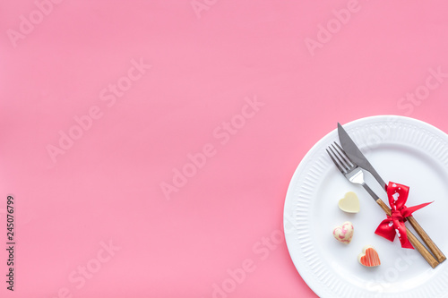 Dating on Valentine's day concept. Festive dishes, tableware on plate on pink background top view copy space
