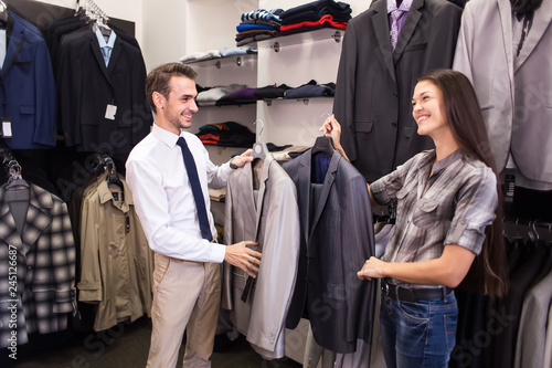 Girl seller helps to pick up a client in a jacket menswear boutique