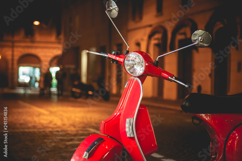 Red Scooter Vespa parked on the old street in Rome, Italy. Night time